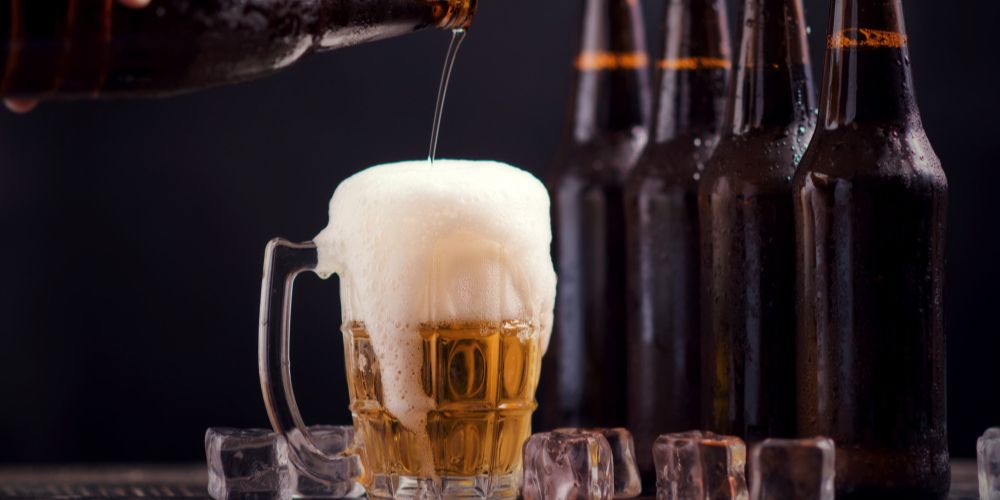 Glass bottles of beer with glass and ice